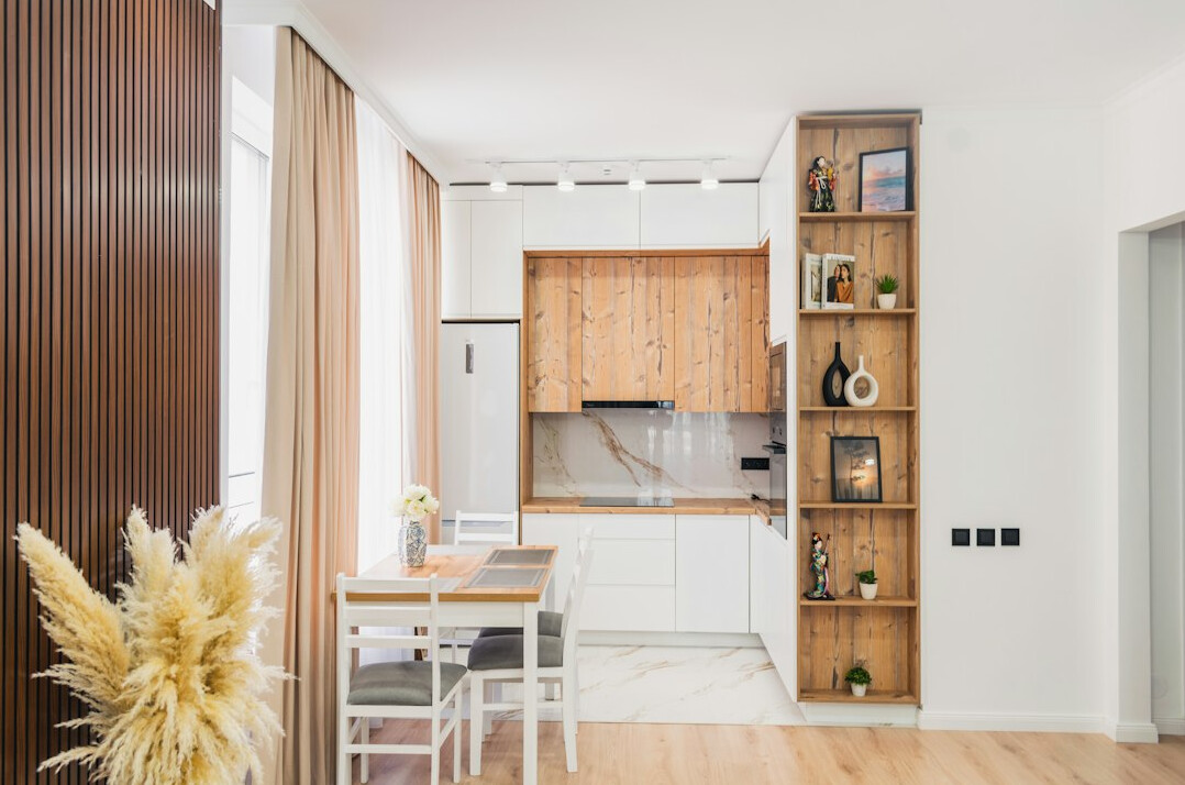 Bright ordinary apartment kitchen with tidy countertop and wooden shelves