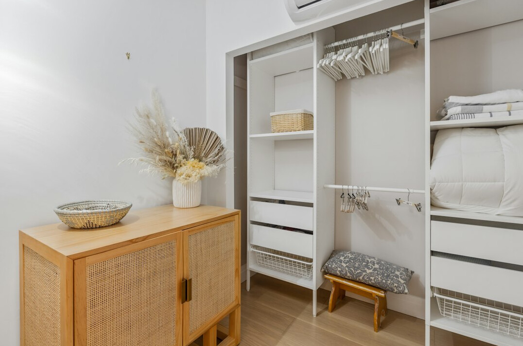 Open wardrobe with folded clothes and hangers